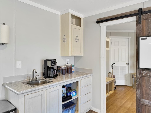 kitchen featuring a barn door, a sink, light wood-style floors, water heater, and light countertops