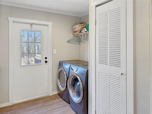 laundry area featuring laundry area, light wood-style flooring, baseboards, and washing machine and clothes dryer