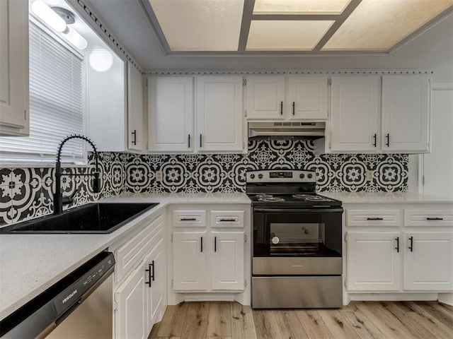 kitchen featuring stainless steel appliances, light countertops, light wood-style floors, a sink, and under cabinet range hood