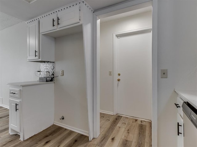 laundry area with light wood finished floors and baseboards