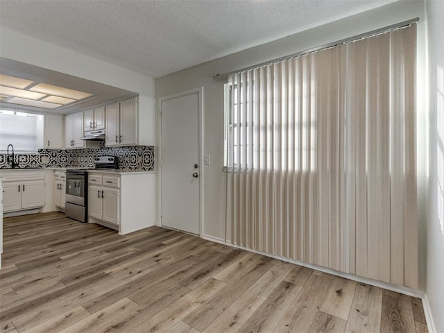 kitchen featuring decorative backsplash, under cabinet range hood, stainless steel electric stove, a textured ceiling, and light wood-style floors