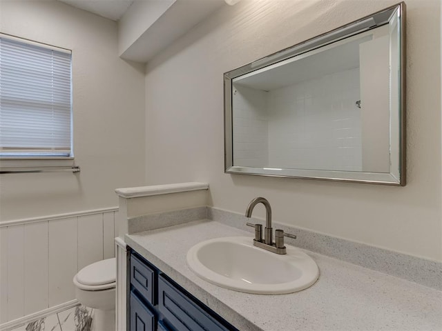 bathroom with marble finish floor, wainscoting, vanity, and toilet