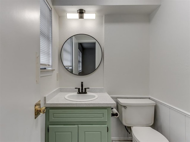 bathroom with wainscoting, vanity, and toilet