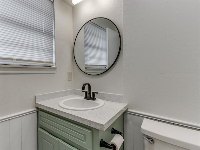 bathroom with toilet, a wainscoted wall, and vanity