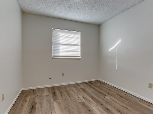 unfurnished room featuring a textured ceiling, light wood-style flooring, and baseboards