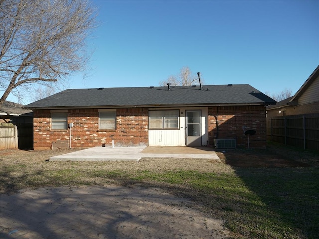 rear view of house with a patio area, a shingled roof, fence, and brick siding