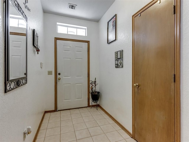 doorway featuring light tile patterned floors, visible vents, and baseboards