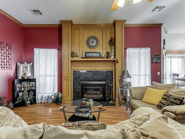 living area with visible vents, crown molding, and wood finished floors