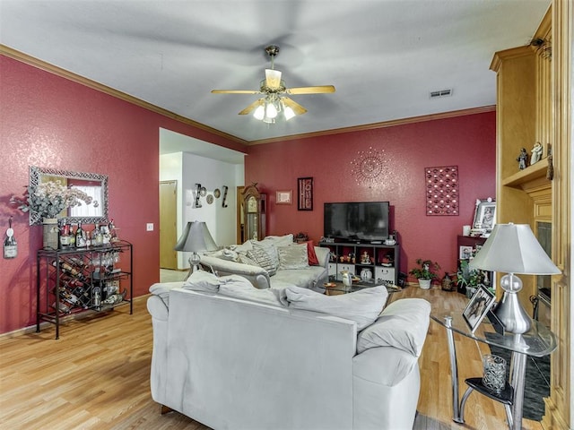 living room with a textured wall, visible vents, wood finished floors, and ornamental molding