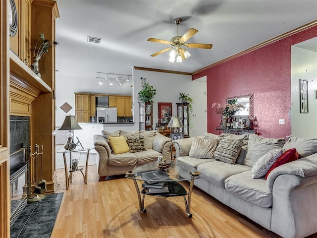 living area featuring visible vents, a fireplace with flush hearth, ceiling fan, ornamental molding, and wood finished floors