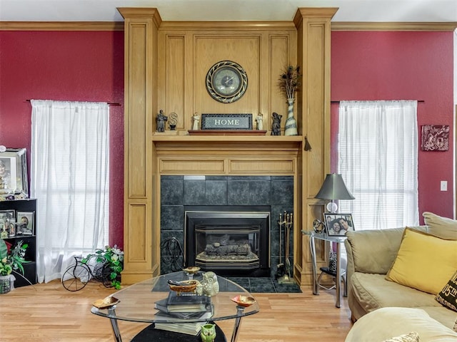 sitting room with crown molding, a tiled fireplace, and wood finished floors