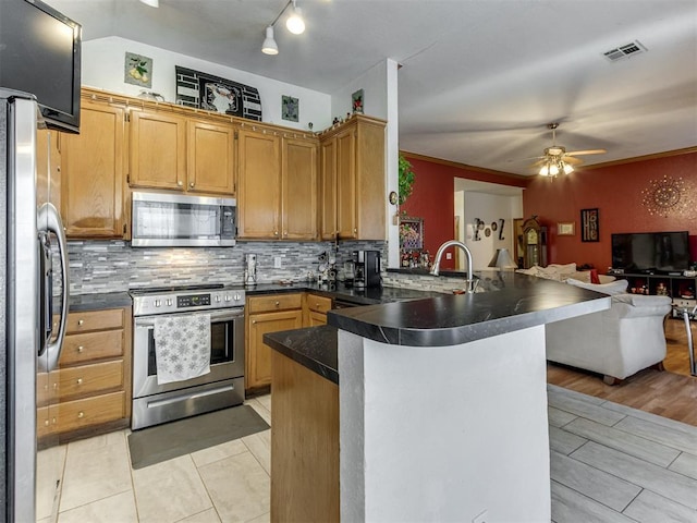 kitchen featuring tasteful backsplash, dark countertops, open floor plan, a peninsula, and stainless steel appliances