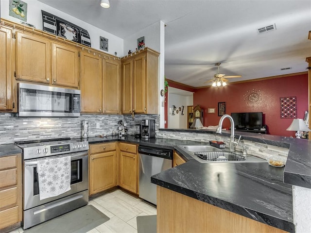 kitchen with stainless steel appliances, a peninsula, a sink, visible vents, and backsplash