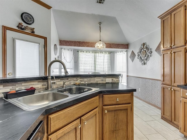 kitchen featuring a wainscoted wall, vaulted ceiling, dark countertops, and a sink