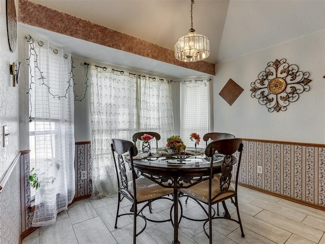 dining area with lofted ceiling and an inviting chandelier