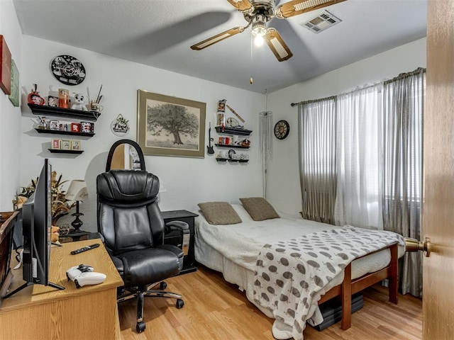 bedroom featuring light wood-style floors, visible vents, and a ceiling fan