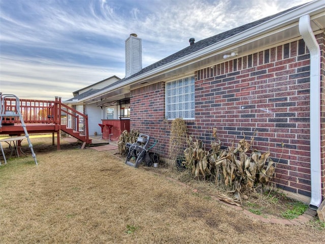 exterior space with a deck, brick siding, and a chimney