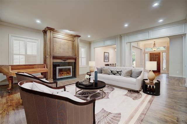 living area with a fireplace, recessed lighting, ornamental molding, wood finished floors, and baseboards