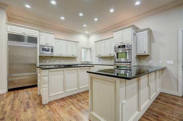 kitchen featuring built in appliances, a peninsula, ornamental molding, and light wood-style floors