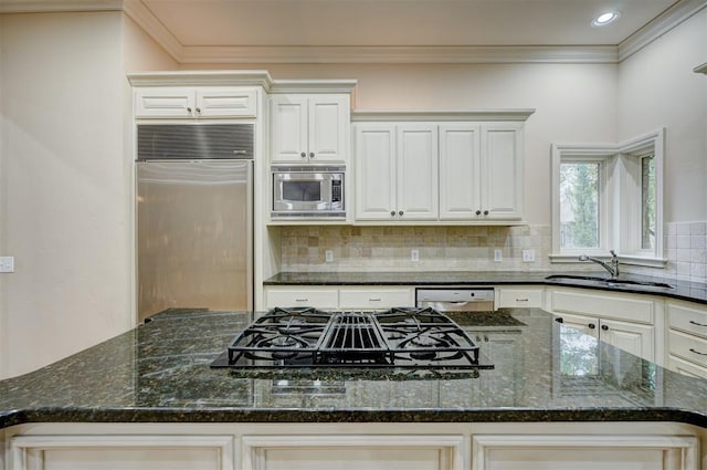 kitchen with built in appliances, tasteful backsplash, dark stone counters, and a sink