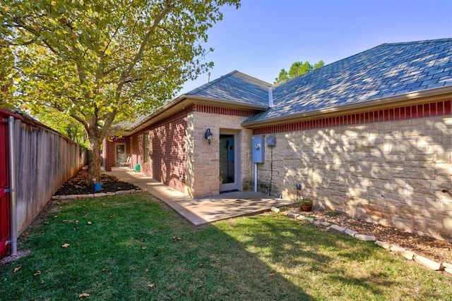 rear view of house featuring a yard, a fenced backyard, a patio, and brick siding