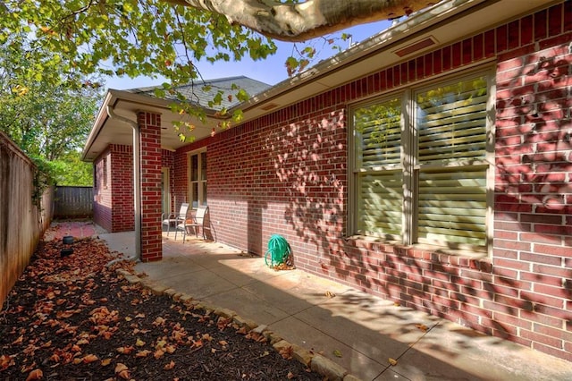 view of home's exterior featuring a patio, brick siding, and a fenced backyard