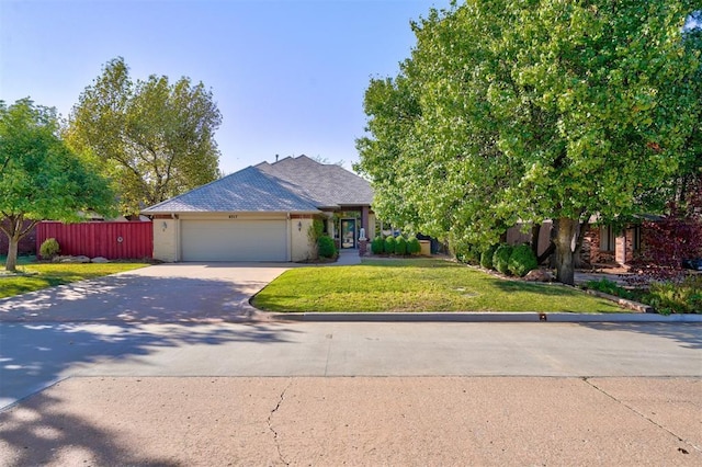 view of front of house with an attached garage, driveway, fence, and a front lawn