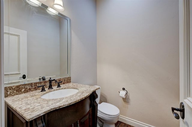 bathroom featuring vanity, toilet, and baseboards