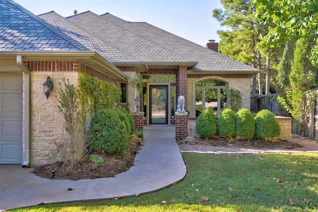 doorway to property featuring brick siding, a yard, a chimney, a garage, and stone siding