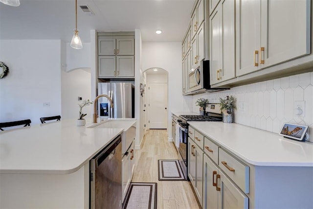 kitchen featuring stainless steel appliances, visible vents, light wood-style floors, gray cabinets, and decorative backsplash