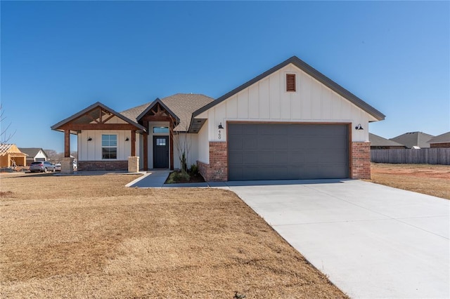 view of front facade with fence, driveway, an attached garage, brick siding, and board and batten siding