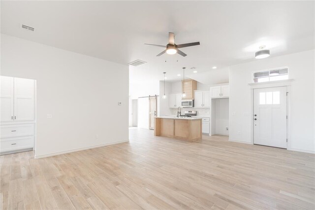 unfurnished living room featuring visible vents, light wood-style flooring, and a ceiling fan