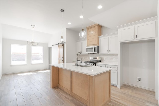 kitchen featuring a sink, a barn door, stainless steel appliances, light countertops, and decorative backsplash