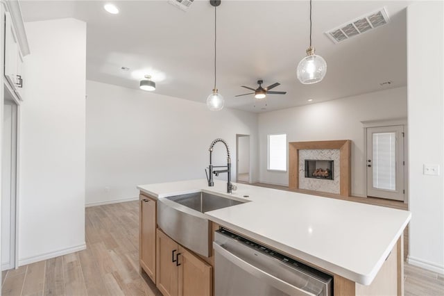 kitchen featuring light wood finished floors, visible vents, a premium fireplace, stainless steel dishwasher, and a sink