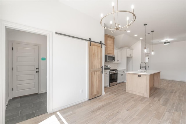 kitchen with an inviting chandelier, a sink, stainless steel appliances, a barn door, and backsplash