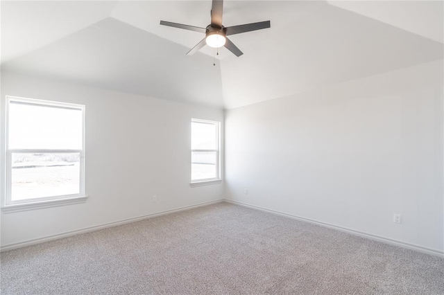 carpeted spare room featuring baseboards, ceiling fan, and vaulted ceiling