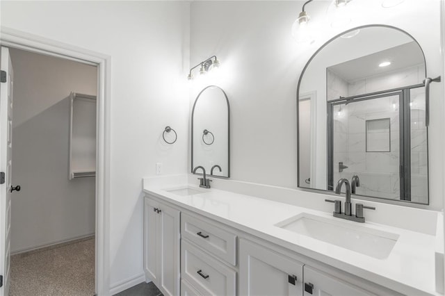 bathroom featuring a sink, baseboards, double vanity, and a shower stall