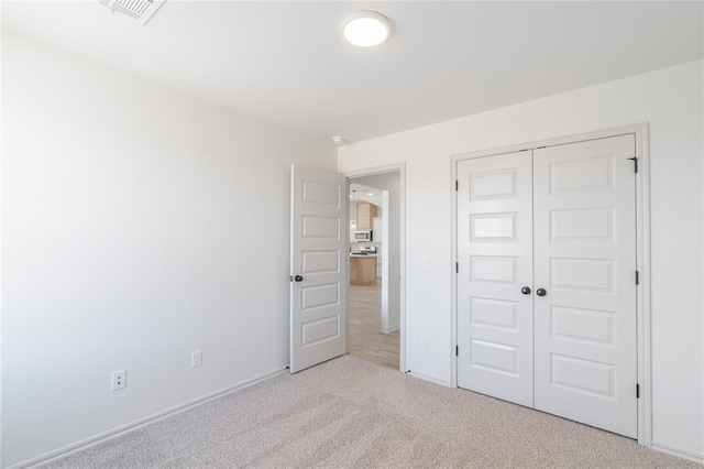 unfurnished bedroom featuring a closet, visible vents, baseboards, and carpet floors