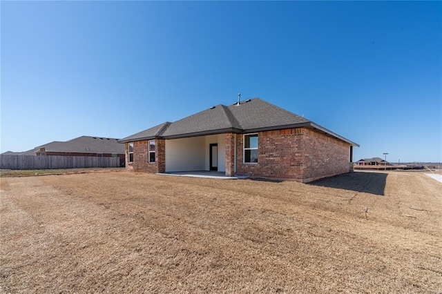 back of property with a patio, fence, brick siding, and a shingled roof