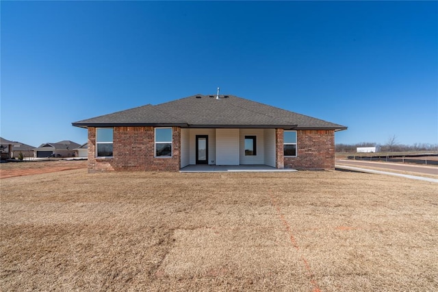 back of property with a patio, brick siding, and a shingled roof