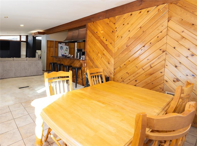 tiled dining space featuring visible vents and wood walls