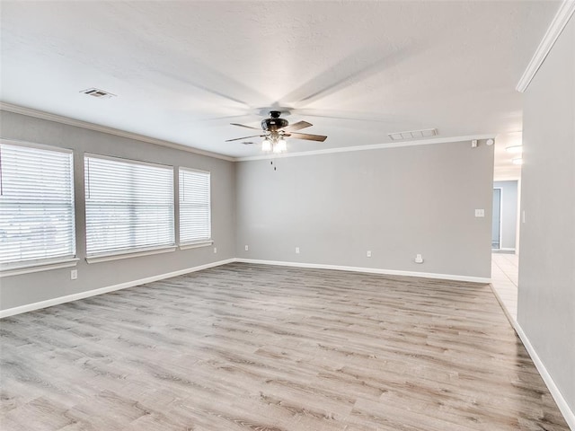 spare room with baseboards, visible vents, wood finished floors, and ornamental molding