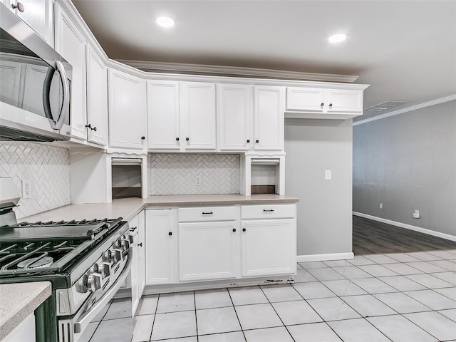 kitchen with white cabinetry, stainless steel appliances, light countertops, and ornamental molding