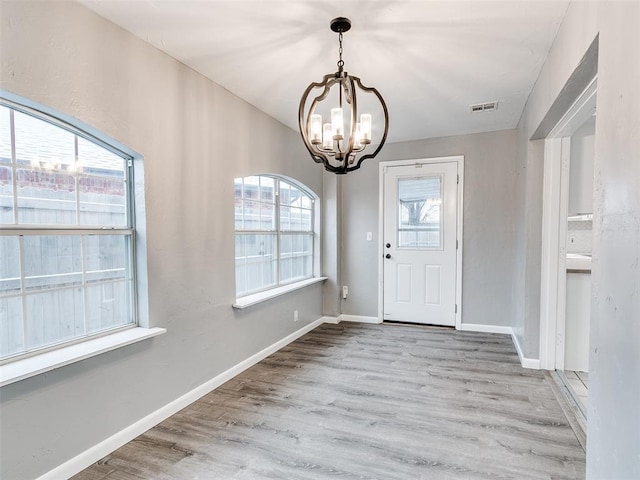 foyer entrance with a chandelier, visible vents, baseboards, and wood finished floors