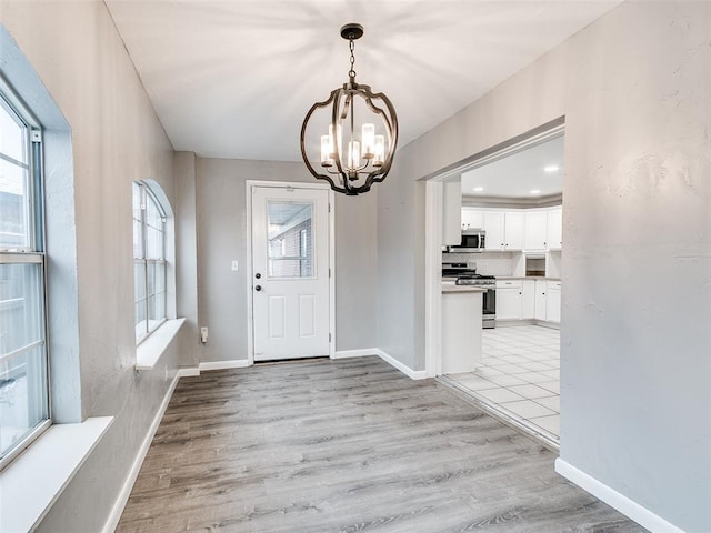 foyer with a chandelier, light wood-style flooring, and baseboards