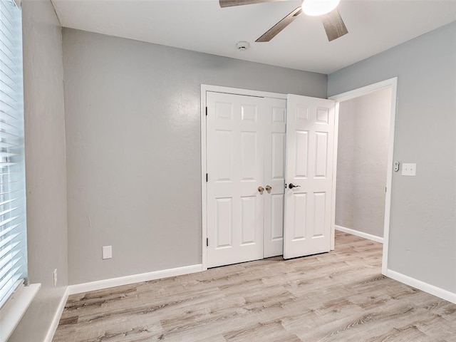 unfurnished bedroom featuring a ceiling fan, a closet, light wood-style flooring, and baseboards