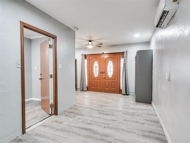 entryway with a ceiling fan, light wood-type flooring, a wall mounted air conditioner, and baseboards