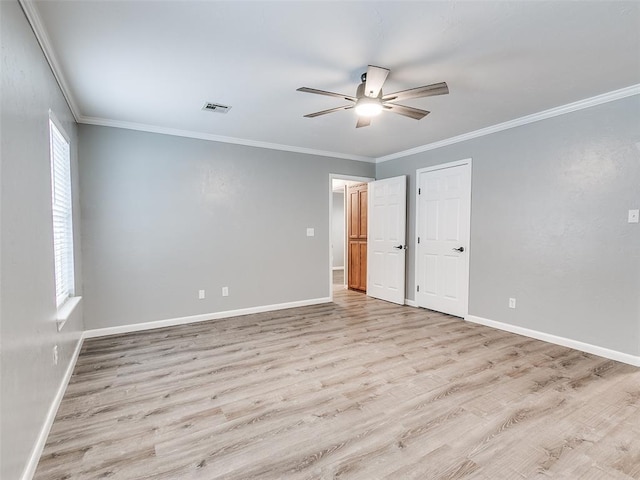 unfurnished room with crown molding, wood finished floors, visible vents, and baseboards