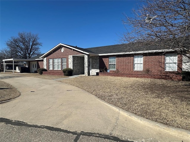 single story home with driveway, stone siding, an attached carport, and brick siding