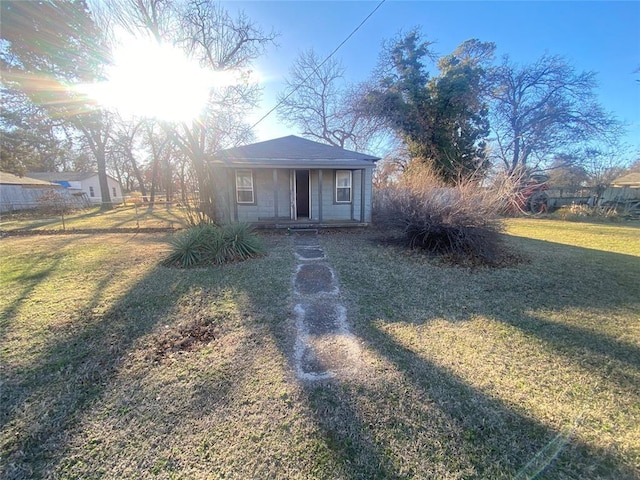 bungalow featuring fence, a front lawn, and an outdoor structure